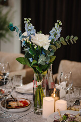 Beautiful flowers with eucalyptus on wedding day. Details closeup. Food and drink on dining table. Set up dinner table reception in restaurant. Serving, setting table in hall. Birthday, baptism, event