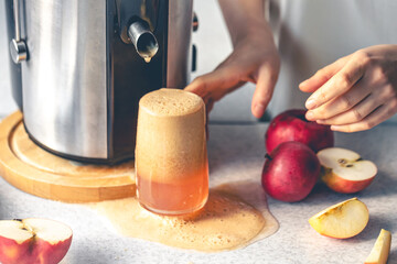 A woman makes apple juice at home with a juicer.