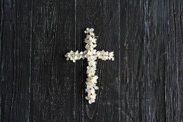 Cross with flowers on a wooden background with the inscription Christ is Risen. Easter concept. Cross symbolizing the death and resurrection of Jesus Christ