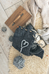 Cozy composition with a knitted element, yarn and a heart made of threads.