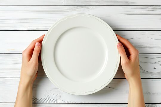 Top view of female hands and empty plate on white wooden table Copy space