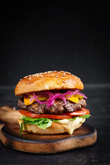 Beef hamburger. Sandwich with beef burger, tomatoes, cheese, pickled cucumber and lettuce. Cheeseburger.