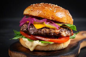 Beef hamburger. Sandwich with beef burger, tomatoes, cheese, pickled cucumber and lettuce. Cheeseburger.
