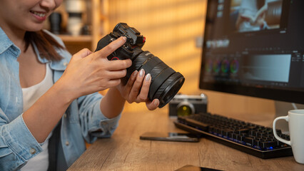 Naklejka premium Close up of photographer woman hands with laptop checking dslr camera on a desk at home