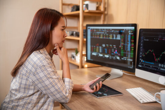 Young woman doing cryptocurrency business trading on her computer at home