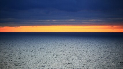 Orange horizon between dark clouds and Baltic sea - 712234157