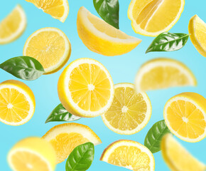 Fresh lemons and green leaves falling on light blue background