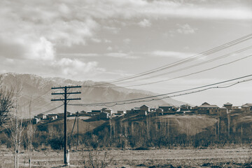 Fototapeta premium a beautiful Village on the top of the mountain and empty field with the electric wire going through
