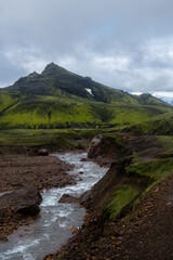 The picturesque landscape on a famous Laugavegur hiking trail. Icelandic landscape of volcanic mountains, riverbed, moss and springs in cloudy weather. Iceland in august. Vertical crop