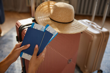 Female holding passport and ticket with boarding pass over packed luggage bags
