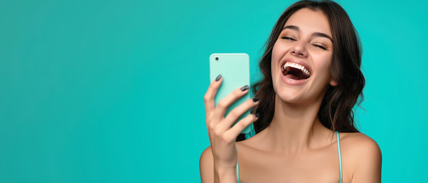 A woman bursts into laughter while she holds a cell phone in her hand, capturing a joyful moment.