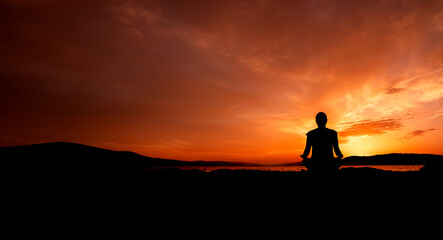 sylwetka kobiety medytującej na plaży przy zachodzie słońca	