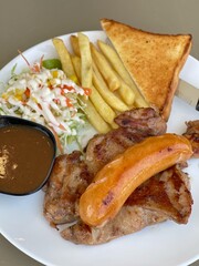 chicken steak and gravy with sausage, salad, French fries on white dish.