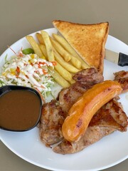 chicken steak and gravy with sausage, salad, French fries on white dish.