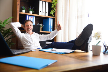 Happy man with hand with ok gesture lying in office