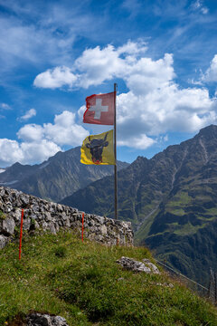Swiss flag an flag of canton uri waving in the wind at a mountain hut in Switzerland