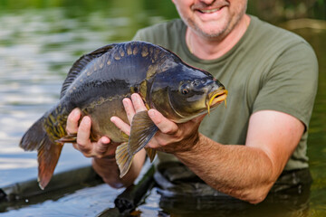 Carpfishing session at the Lake.lucky fisherman holding a giant common carp.Angler with a big carp fishing trophy.Fishing adventures.Fish trophy
