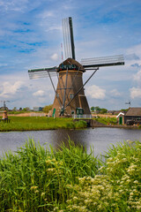 View of traditional windmills and canals in Kinderdijk Village in the Netherlands, South Holland. Famous tourist attraction in Holland. Beautiful Dutch landscape with canal and grass.