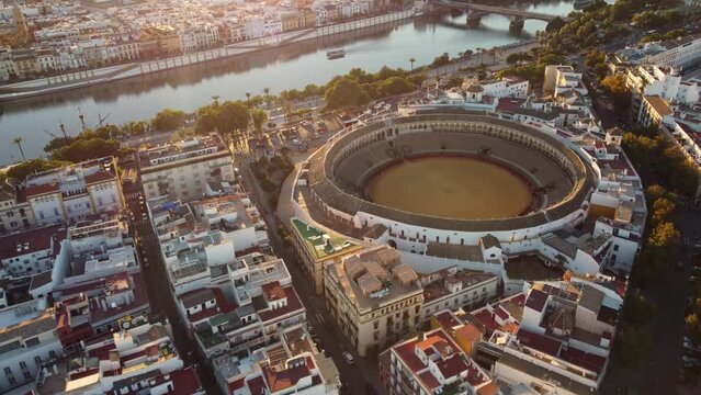 Seville, Spain: Aerial drone footage of the Seville historic city center with the Plaza de Toros, the bullfighting area close to the  Guadalquivir river in Andalusia largest city at sunset. 