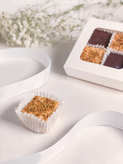 Bird's milk candy sprinkled with crushed pistachios in a capsule on the background of a gift box