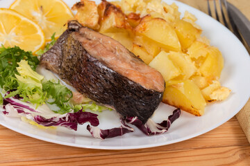 Serving of baked rainbow trout with potato, fragment close-up