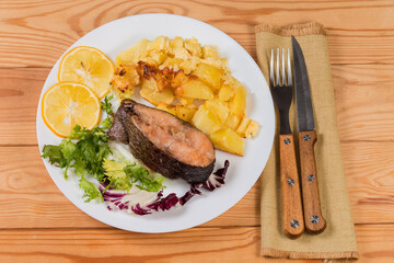 Baked trout with potato serving, top view on rustic table