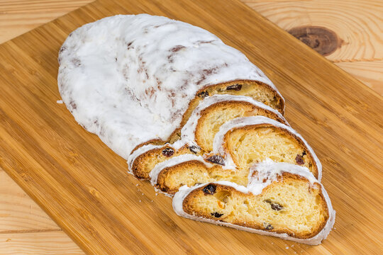 Partly sliced Christmas stollen with raisins on cutting board