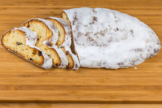 Partly sliced Christmas stollen with raisins on cutting board