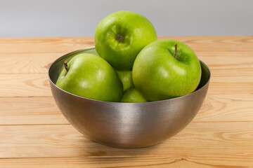 Green apples in metal bowl, side view on rustic table