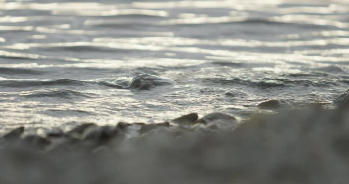 calm scene of a peaceful lake with waves washing up on a pebble beach