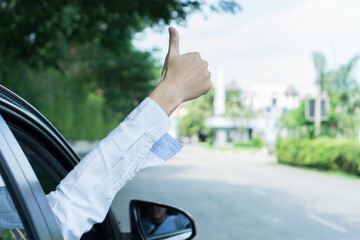 Hand of male traveler with thumbs up from car go to travel. Hand man wear white shirt driving and thumbs up. Travel by car, buying and selling cars, car insurance concept.