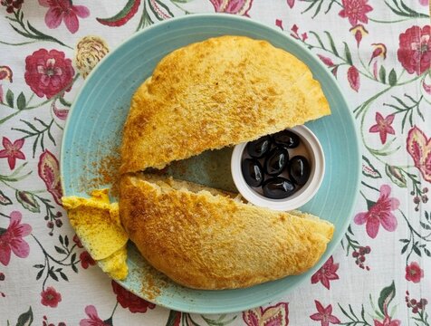 Bulgarian bread, Parlenka pita, presented on a plate with butter, salt, and black olives.
