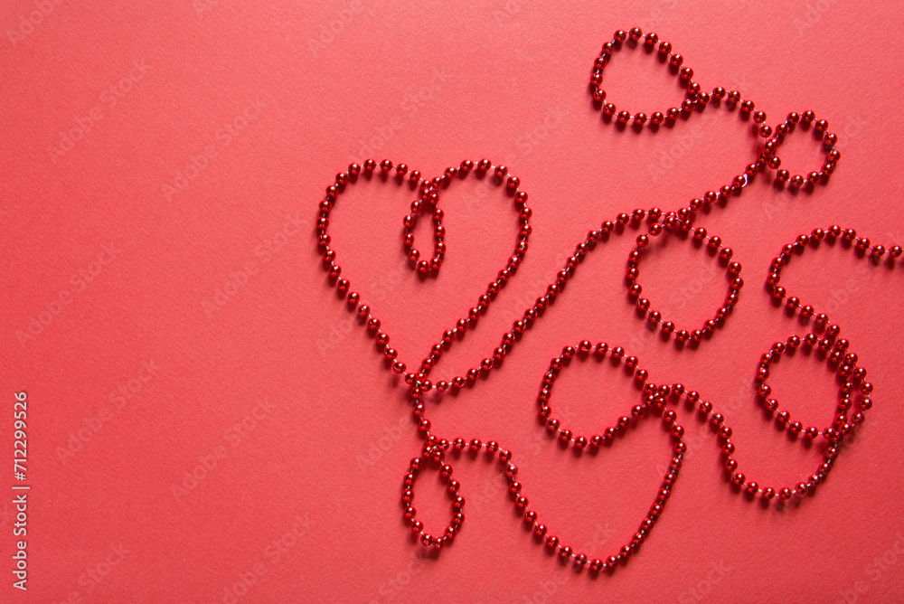 Poster Heart shape with red ribbon made of beads on red background. Valentines day concept, empty card mockup	