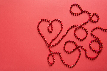 Heart shape with red ribbon made of beads on red background. Valentines day concept, empty card mockup	