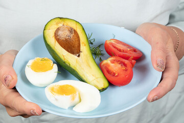 On the plate is a healthy breakfast of eggs, tomatoes and avocado. Healthy eating.