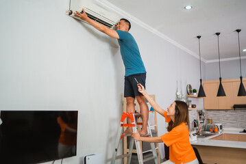 asian woman helping partner repairing their broken airconditioner