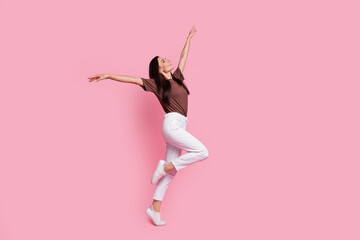 Full body profile portrait of overjoyed pretty lady raise hands enjoy dancing empty space isolated on pink color background