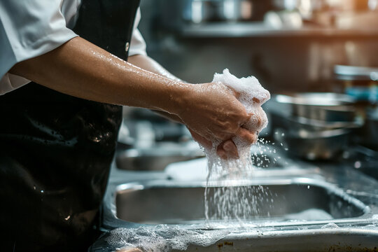 Cozinheiro lavando as mãos na torneira da cozinha