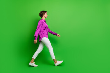 Fototapeta na wymiar Profile side full length photo of adorable cute stylish girl walking moving looking empty space isolated on green color background