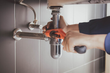 plumber at work in a bathroom, plumbing repair service , fix water plumbing leaks, replace the kitchen sink drain - obrazy, fototapety, plakaty
