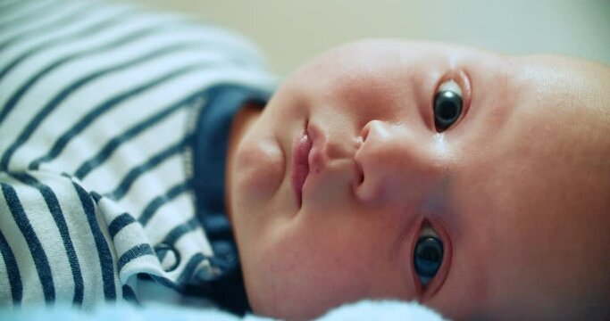 A half-year-old boy looks directly into the camera in close-up. Little cute baby.