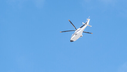 White helicopter on blue sky background, Close-up, selective focus, tinted image. Helicopter flight, delivery of passengers by air