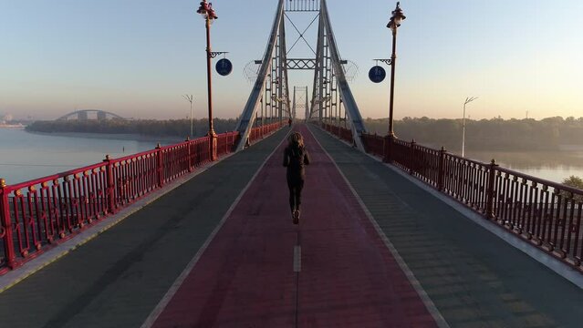 Footage of female jogger running on a bridge in Kyiv, Ukraine early in a morning