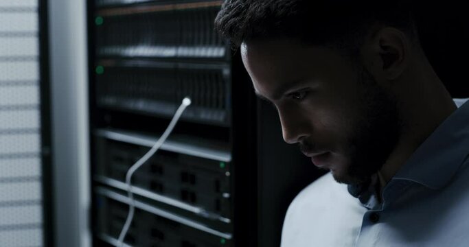 Technician, server room and typing on laptop for system maintenance, hardware or software backup in cybersecurity. Man or programmer on computer for engineering, coding and programming in data center