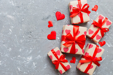 Top view photo of valentine day decorations gift box with red ribbon bow on colored background....