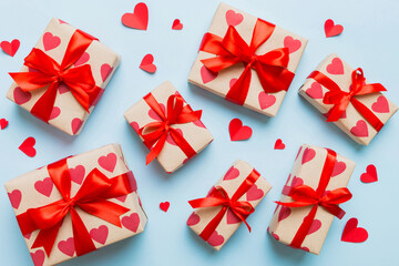 Top view photo of valentine day decorations gift box with red ribbon bow on colored background....