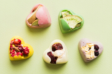 chocolate sweets in the form of a heart with fruits and nuts on a colored background. top view with space for text, holiday concept