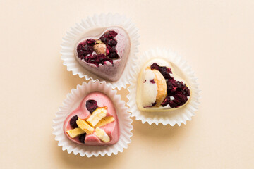 chocolate sweets in the form of a heart with fruits and nuts on a colored background. top view with space for text, holiday concept