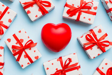 gift box with red bow and red heart on colored background . Top view. Flat lay