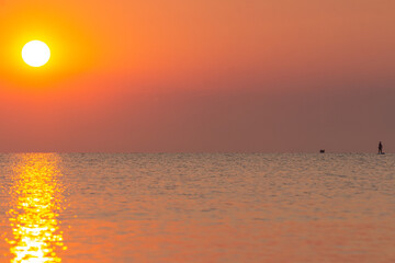 A beautiful dawn over the Black Sea in Odessa. Silhouette of a person riding on a SAP. Ukraine